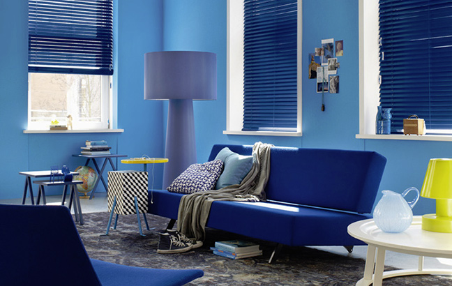 Temno modre žaluzije in pohištvo naredijo prijeten kontrast s svetlo modro steno.